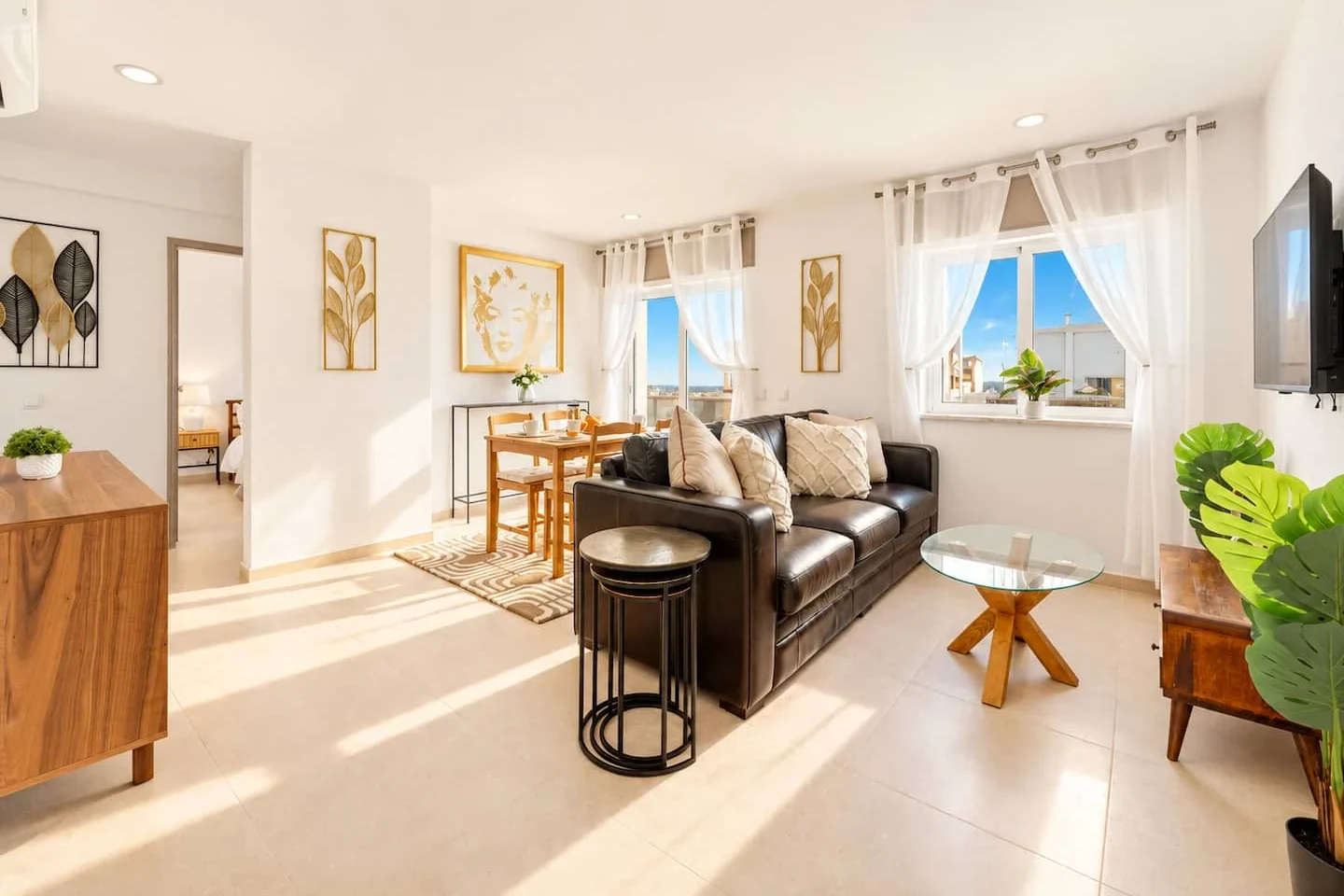 Sunlit living room with a dark sofa and dining table at Boutique Penthouse