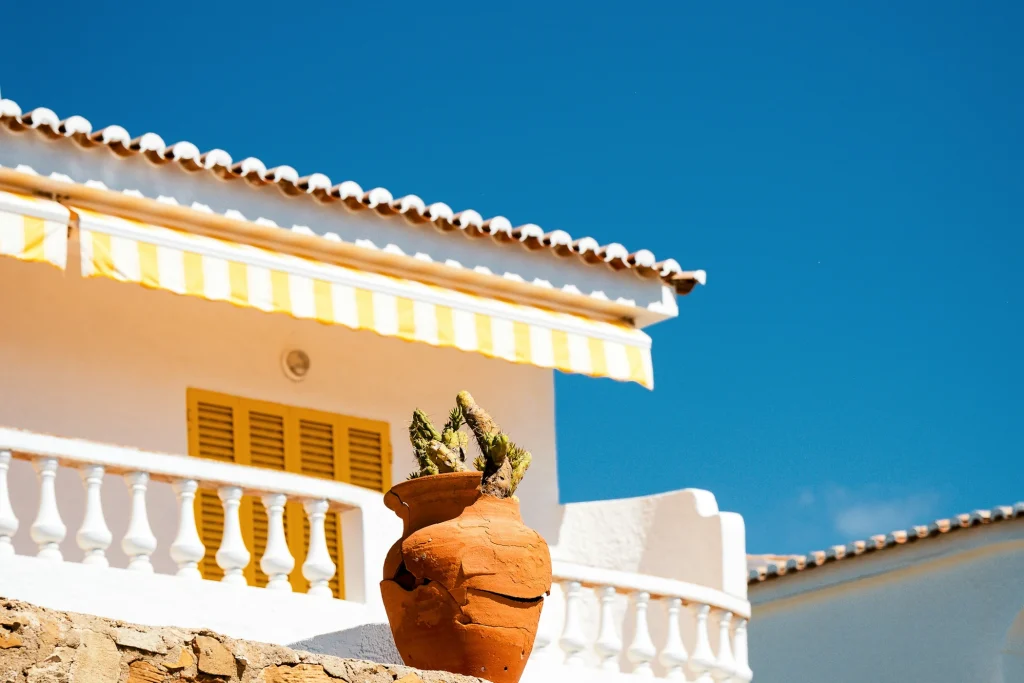 White façade, yellow awning and terracotta cactus pot beneath a blue sky in Lagos
