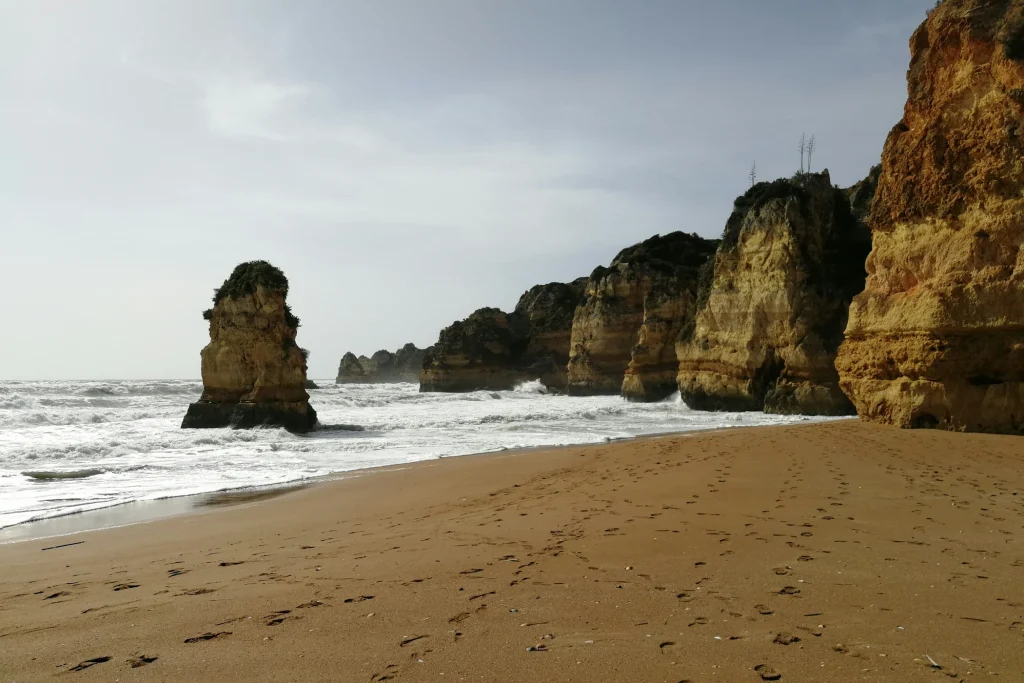Sand, waves and coastal rock formations at Praia de Dona Ana in Lagos