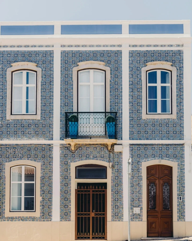 Blue tiled façade with tall windows and wooden doors in Lagos