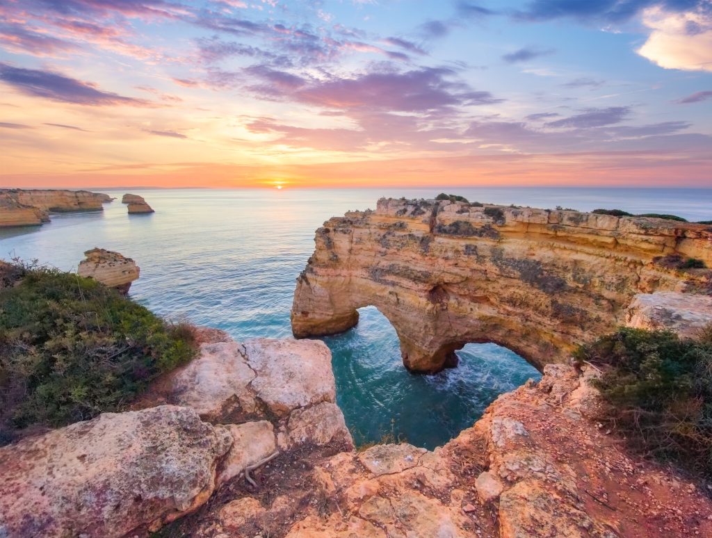 Sea arches and limestone cliffs at sunset at Praia da Marinha, Lagoa.