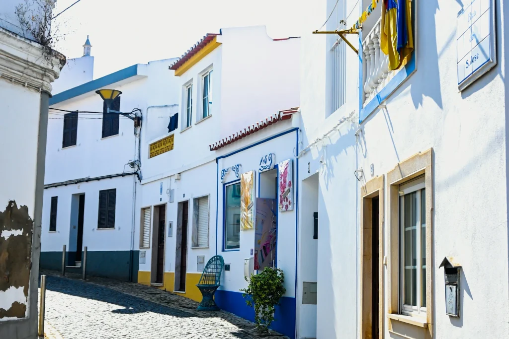 Cobbled street and whitewashed houses with blue and yellow trim in Lagos Old Town