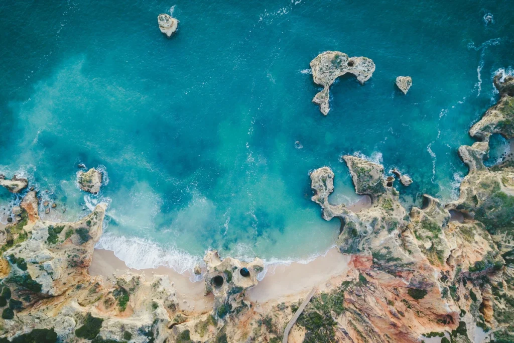 Aerial view of turquoise water and coastal rocks at Praia do Camilo in Lagos