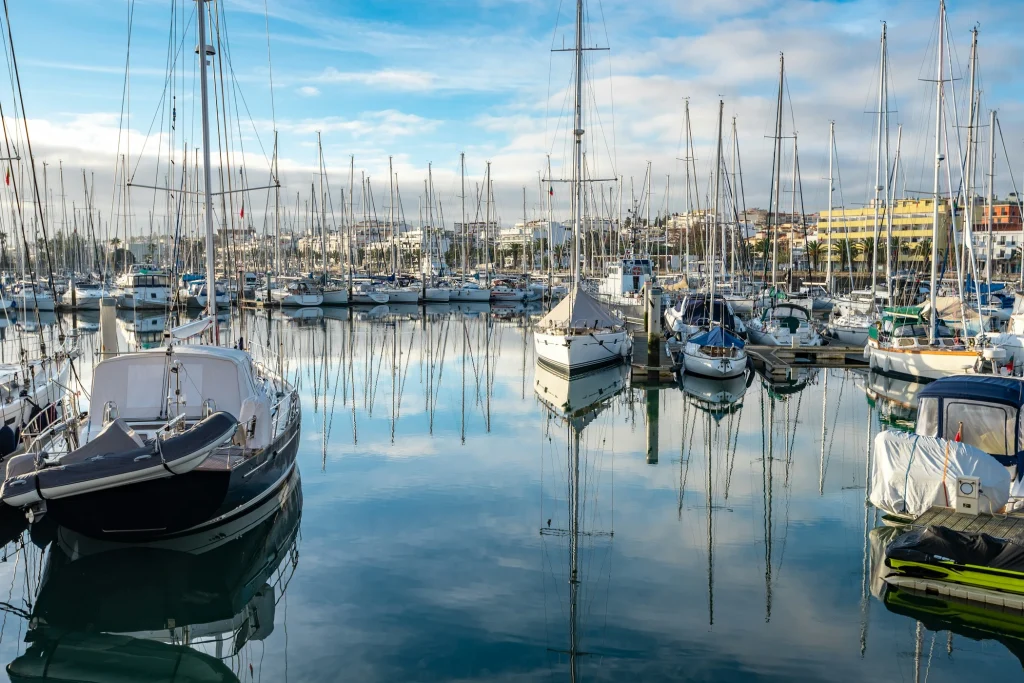 Sailing boats moored at Marina de Lagos, reflected in the water